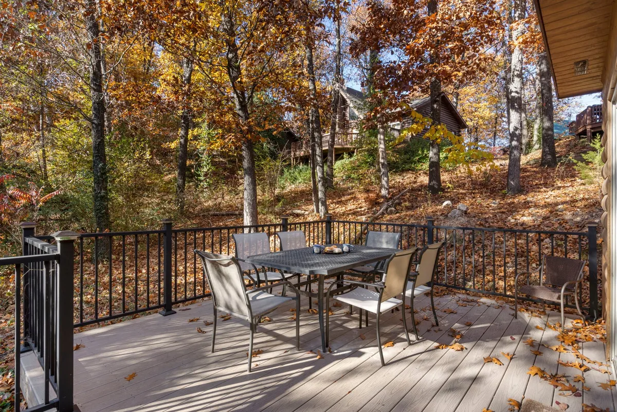 A spacious outdoor deck with a dining table and chairs overlooks autumn foliage, providing a serene space for group meals or morning coffee amid nature’s beauty.