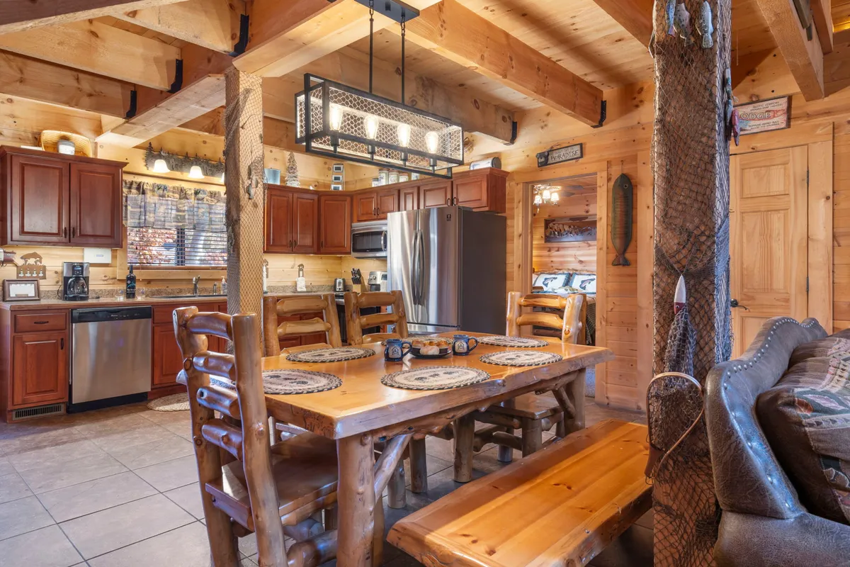This image captures a welcoming dining area with a substantial wooden dining table, surrounded by cabinets and a comfortable sofa. A stylish light fixture adds warmth, and the space feels ready for family meals and heartfelt conversations.