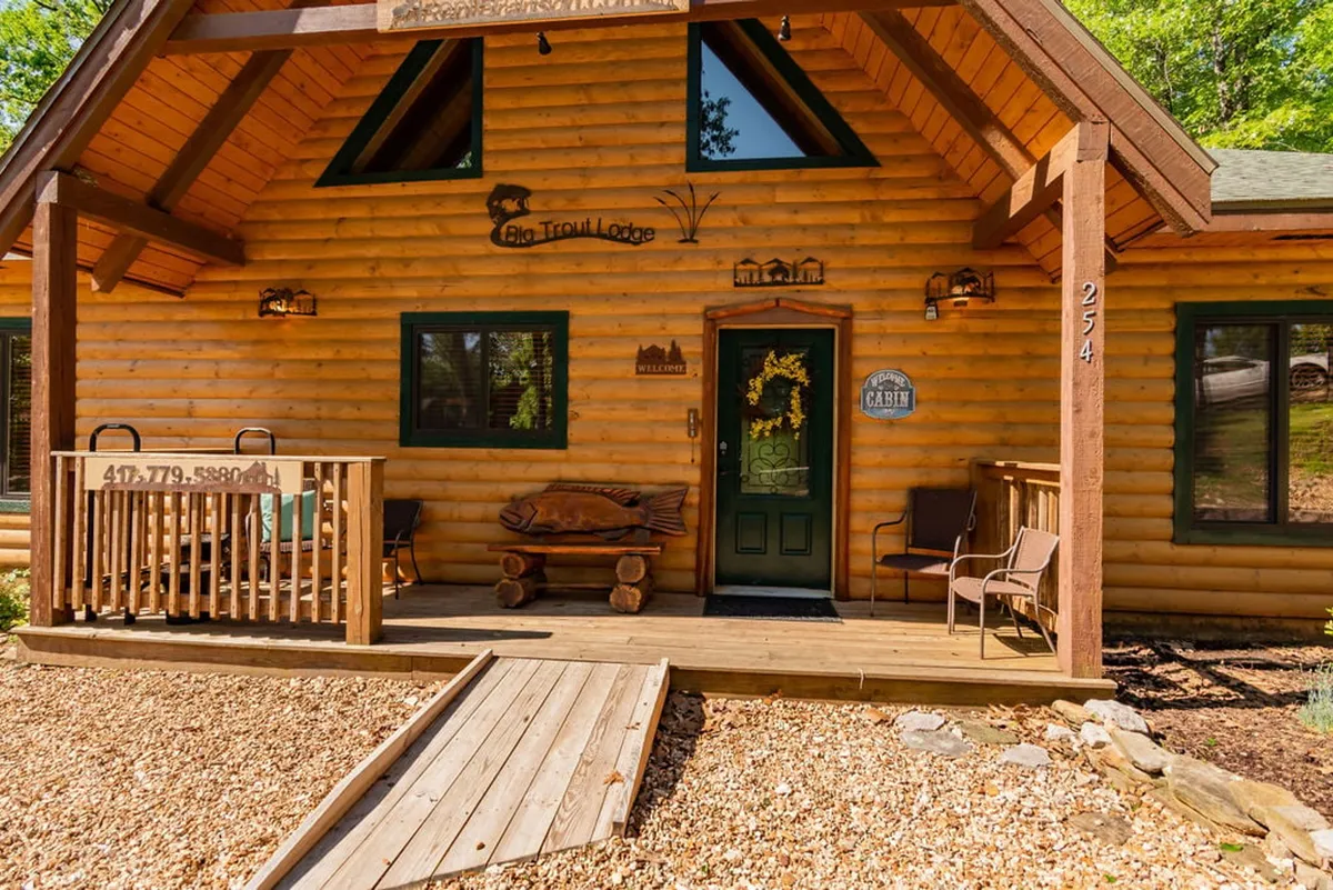 This image features the log cabin's exterior with a prominent welcome sign, wooden decor, and inviting front porch seating, providing a glimpse of the spacious driveway area ideal for parking and easy access.