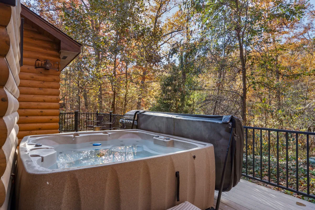 A tranquil scene highlighting a hot tub set on a wooden deck amidst tall trees. The setup encourages soaking in the bubbling spa while enjoying nature views and stargazing, with hints of adjacent seating and relaxation spaces.