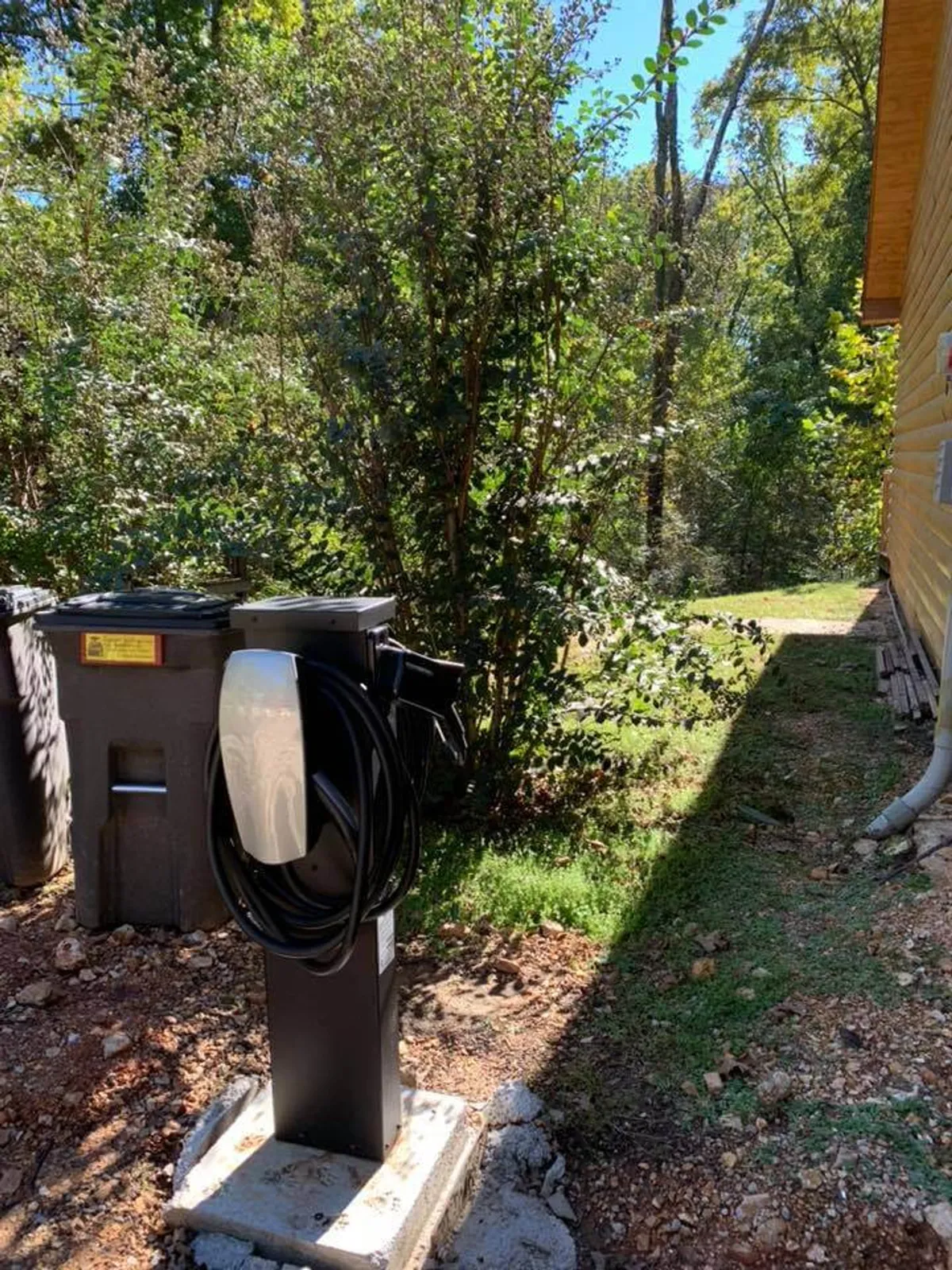 An electric vehicle charging station set amidst greenery, showing the thoughtful, eco-friendly amenities available at the resort. The image includes glimpses of nature and convenient infrastructure.